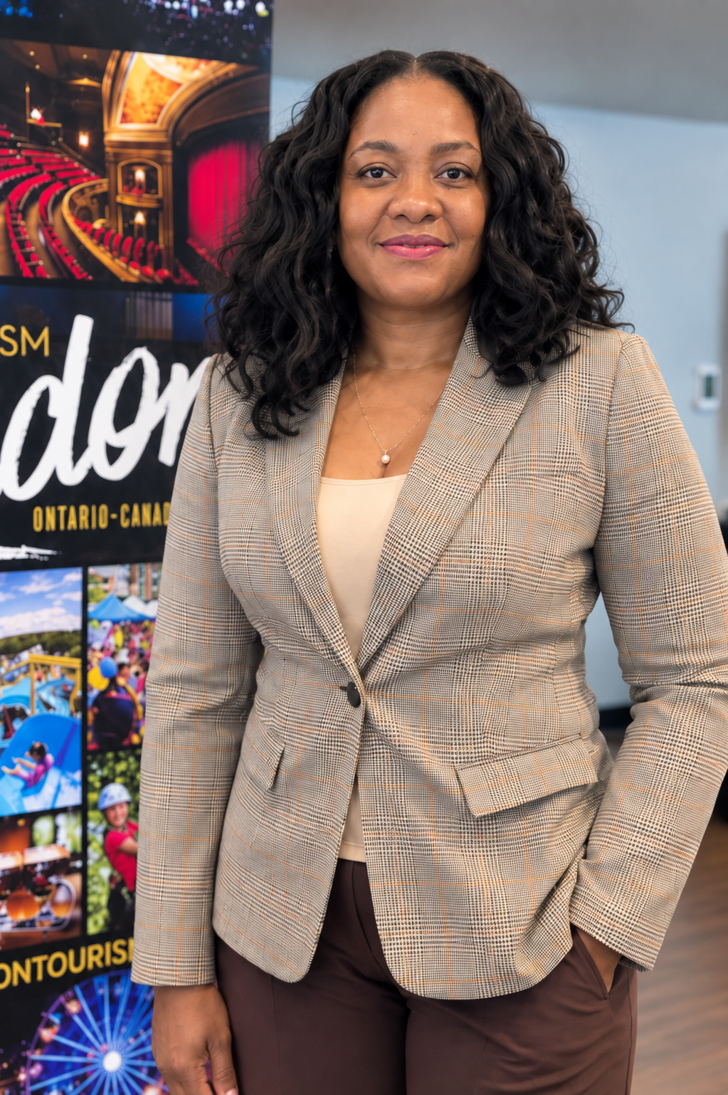 Nadia in a checked blazer and brown pants in front of a Tourism London banner